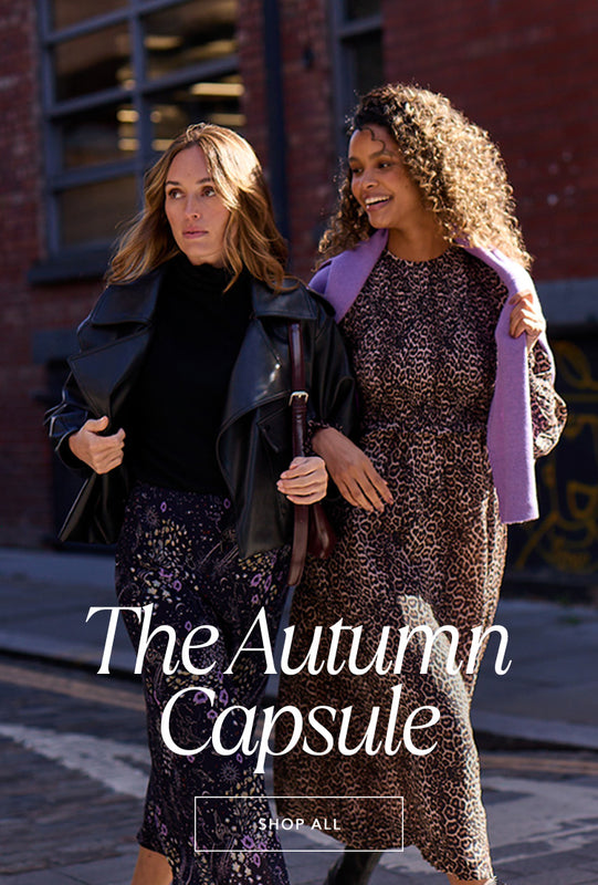 Model on left wears our Zodiac Print Midi Skirt, styled with Black Alexia Roll Neck Knit Top. Model on right wears Elsie Shirred Bodice Big Cat Print Midi Dress, paired with Purple Stella Roll Neck Jumper. Copy on image 'The Autumn Capsule - Shop All'